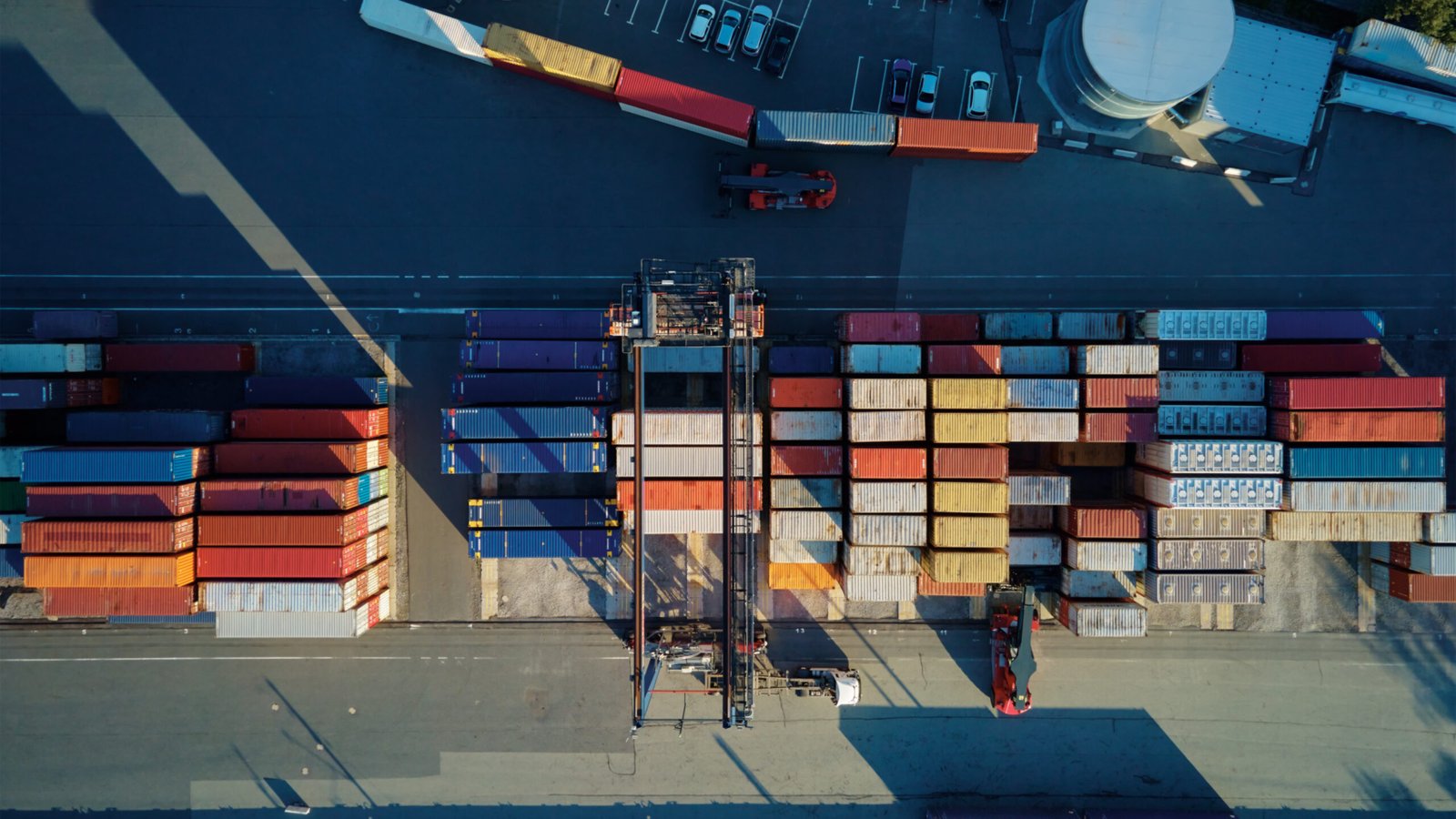 Shipping containers in terminal, Unloading containers in warehouse on railroad platform with cranes and forklifts, aerial view